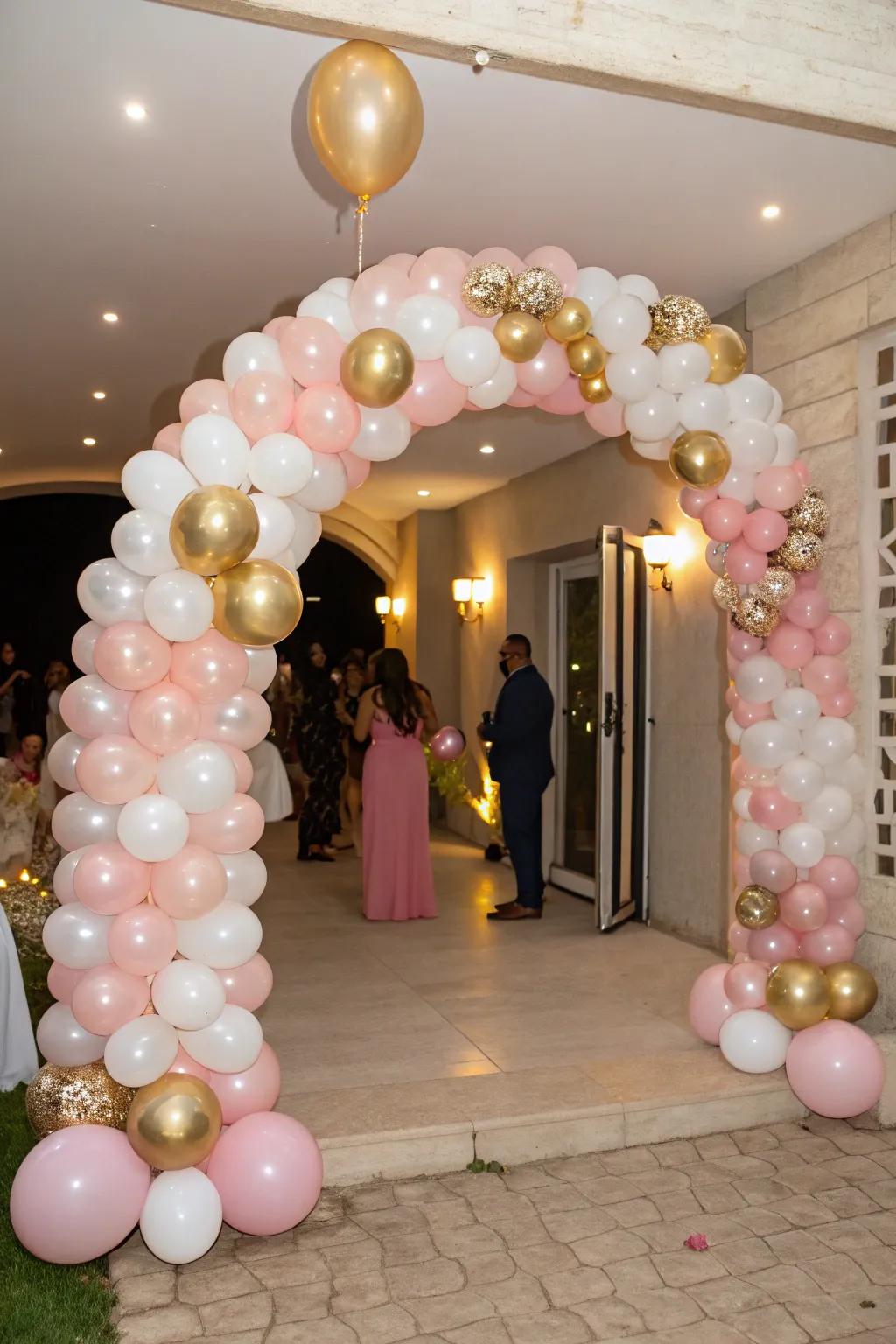 A captivating balloon arch in delicate pink, luxurious gold, and serene white warmly greets party attendees.