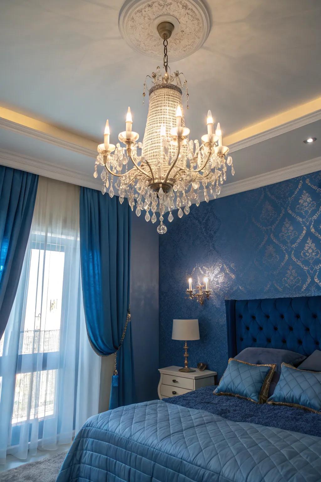 A crystal chandelier injects a touch of refinement into a bedroom adorned with royal blue accents.